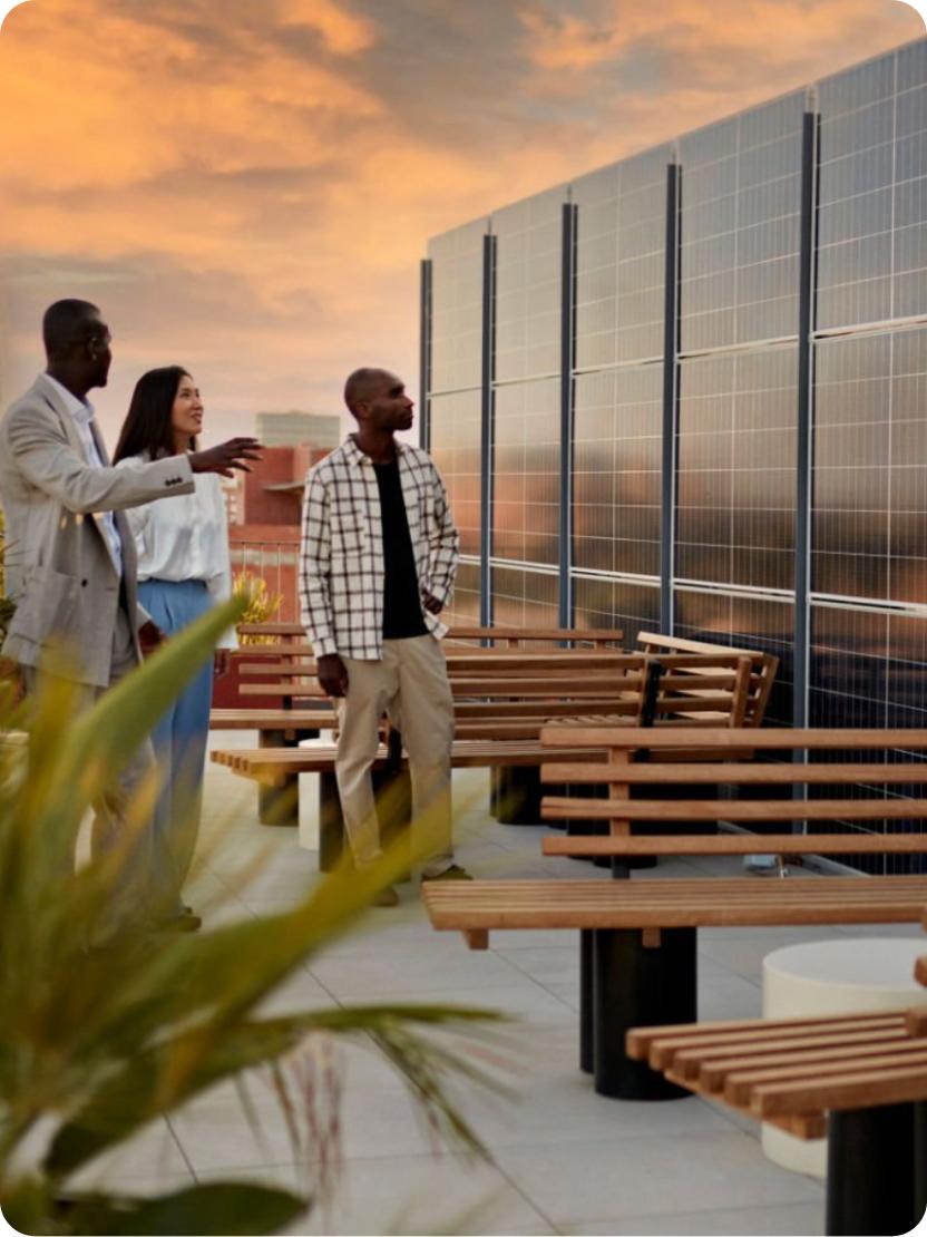 groupe de trois personnes observant des panneaux solaires sur une terrasse